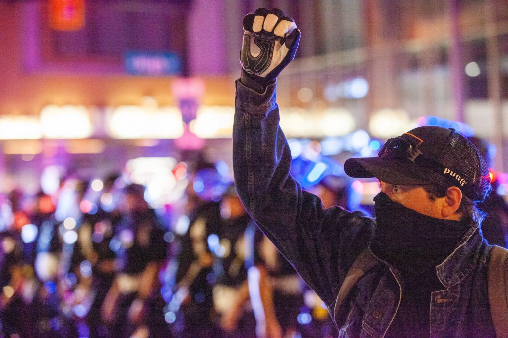 Protester raises his fist on High St. with a line of Police...