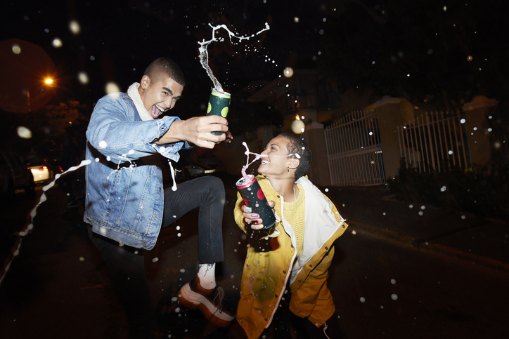 Cheerful male and female splashing drink