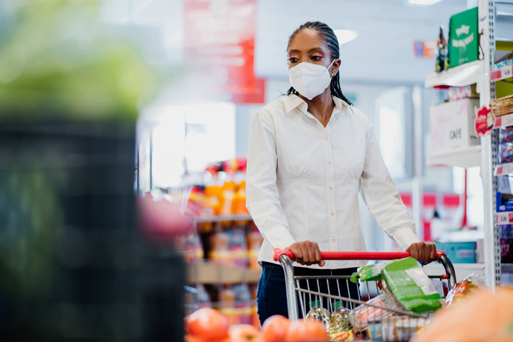 Woman shopping in supermarket wearing coronavirus face mask.