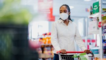 Woman shopping in supermarket wearing coronavirus face mask.