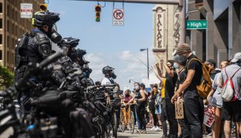 Protesters confront police officers standing in the middle...