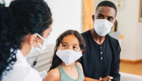 Doctor on house call examining small girl during pandemic