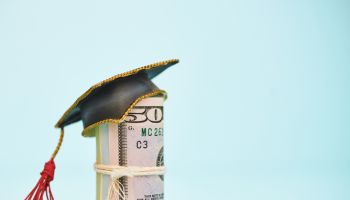Cost of Education. Money roll wearing a mortarboard graduation cap