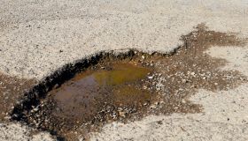 Pothole filled with water on damaged road