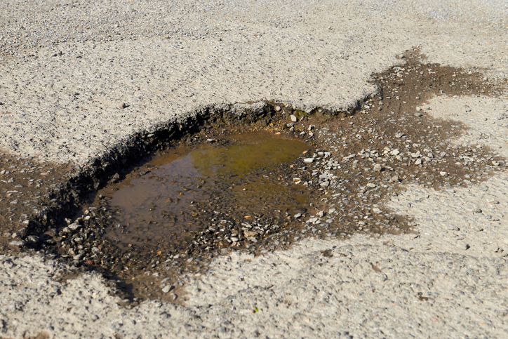 Pothole filled with water on damaged road