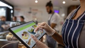 Close-up on a waitress using a tablet to take an order at a restaurant