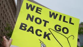 A protester holds a placard that says "We will not go back"...