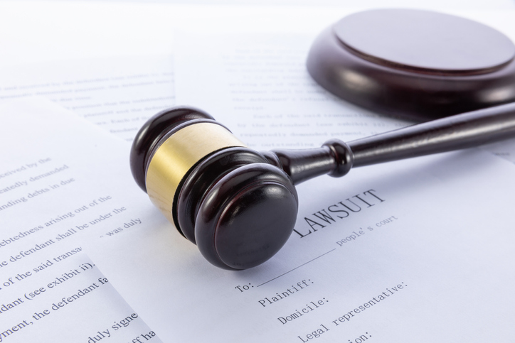 Closeup shot of a gavel and lawsuit papers on a white surface