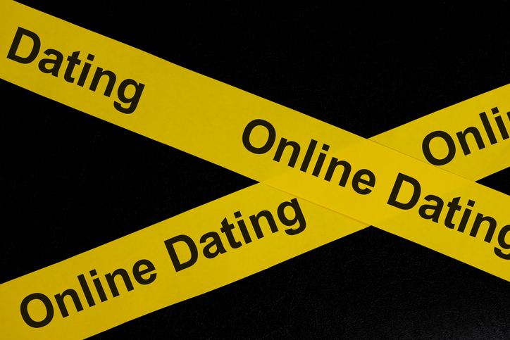 Online dating alert, caution and warning concept. Yellow barricade tape with word in dark black background.