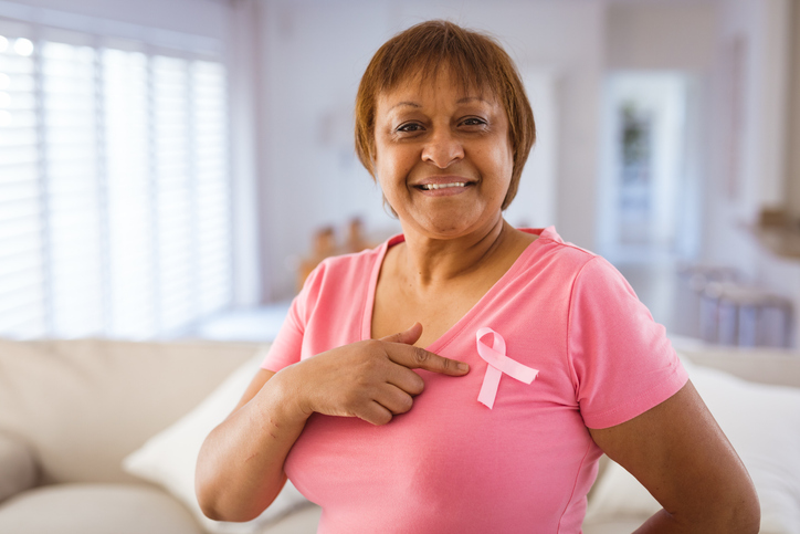 African american senior woman pointing at breast cancer awareness ribbon on pink t-shirt